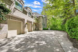 View of property exterior with a garage, concrete driveway, brick siding, and a high end roof