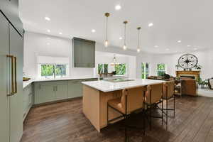 Kitchen with a center island, high end refrigerator, a kitchen breakfast bar, decorative backsplash, and dark wood finished floors