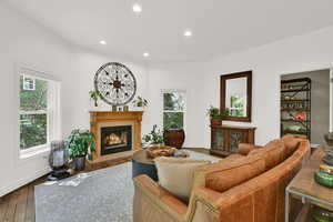 Living area featuring wood-type flooring, a fireplace with flush hearth, and recessed lighting