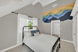 Bedroom with vaulted ceiling, light colored carpet, and ensuite bathroom