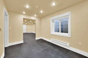 Unfurnished room featuring a baseboard heating unit and recessed lighting