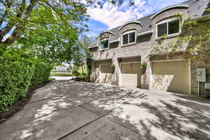 View of side of property featuring brick siding, driveway, and an attached garage