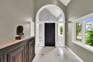 Foyer entrance with light tile patterned floors and lofted ceiling