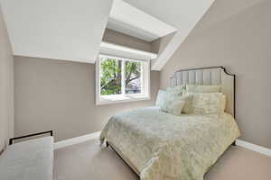 Bedroom with lofted ceiling and light colored carpet