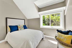 Carpeted bedroom featuring baseboards and lofted ceiling