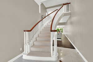 Stairway featuring tile patterned floors and a high ceiling