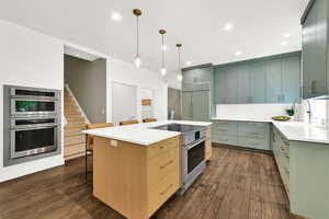 Kitchen with light stone counters, decorative backsplash, a breakfast bar area, dark wood finished floors, and stainless steel appliances