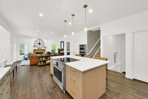 Kitchen with a kitchen bar, a center island, hanging light fixtures, open floor plan, and dark wood-type flooring