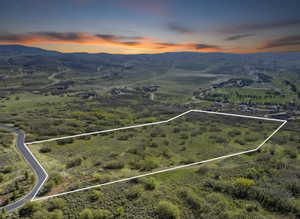 Aerial view of property and surrounding area with property parcel outlined and a mountainous background