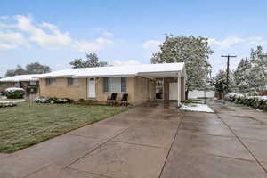 Single story home featuring driveway, a carport, and brick siding