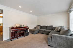 Living area with carpet floors, ornamental molding, and recessed lighting