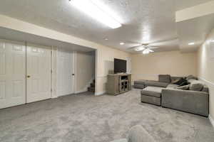 Living room featuring a textured ceiling, light carpet, and a ceiling fan
