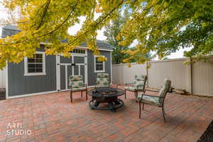 Fenced backyard with a patio, an outdoor fire pit, and a storage shed