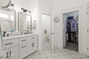 Bathroom with double vanity, a walk in closet, and tiled shower