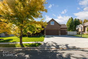 View of front facade featuring a front yard, brick siding, concrete driveway, and an attached garage