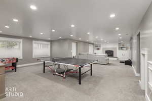 Game room featuring recessed lighting, light carpet, a glass covered fireplace, and built in features