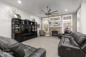 Carpeted living area with ceiling fan and a fireplace