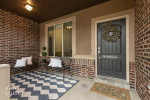 View of exterior entry featuring brick siding and a porch