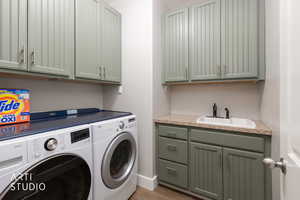 Laundry room with washing machine and clothes dryer, cabinet space, and light wood finished floors