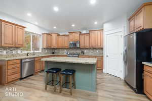 Kitchen with wood finish cabinetry, stainless steel appliances, a kitchen breakfast bar, a kitchen island, and light wood-style floors