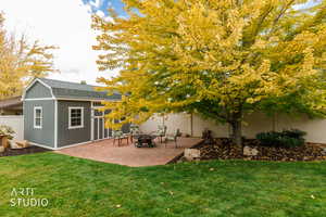 Fenced backyard with an outdoor structure, a patio, and an outdoor fire pit
