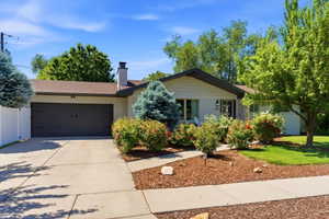 Single-story residence featuring a two-car garage with dark doors, a concrete driveway, and a light-colored exterior
