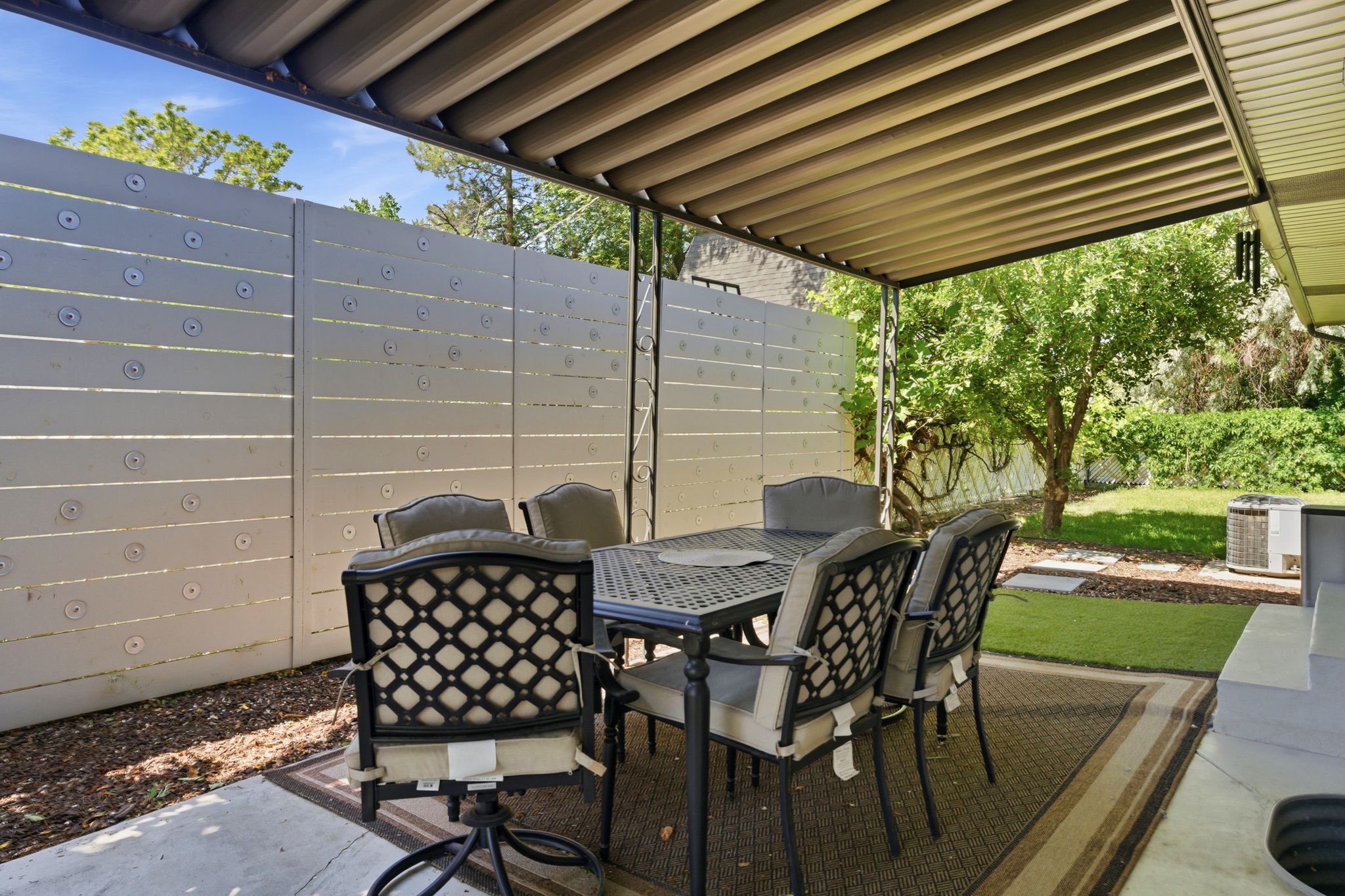 Covered patio featuring an adjustable louvered awning, concrete flooring, and a privacy fence