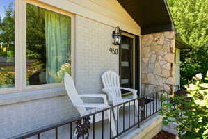 Front entry featuring a stone facade, painted brick exterior, dark-framed door with numerical address, and a black wrought iron railing
