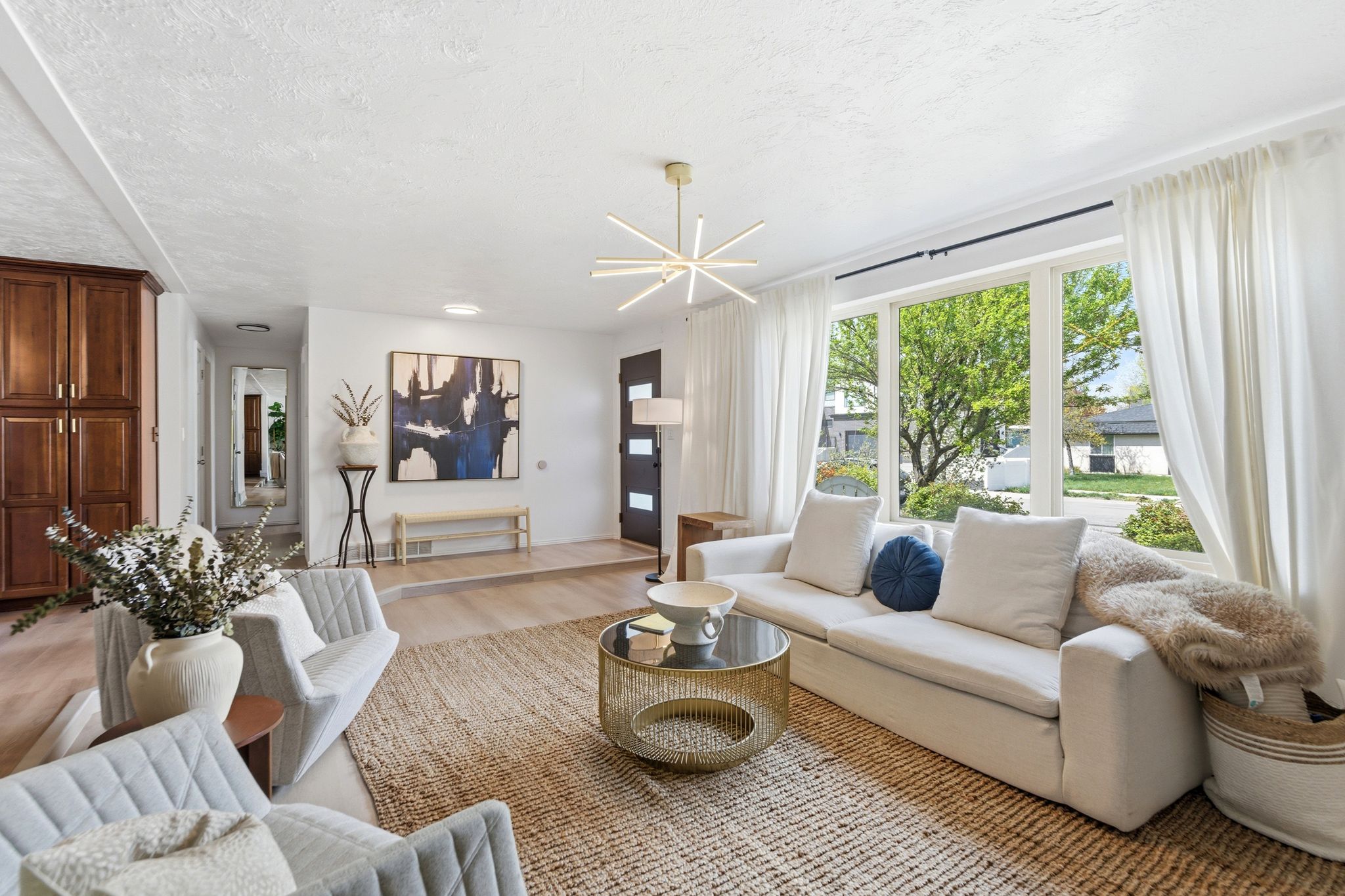 Living area with light wood-style floors, a textured ceiling, and hanging lights