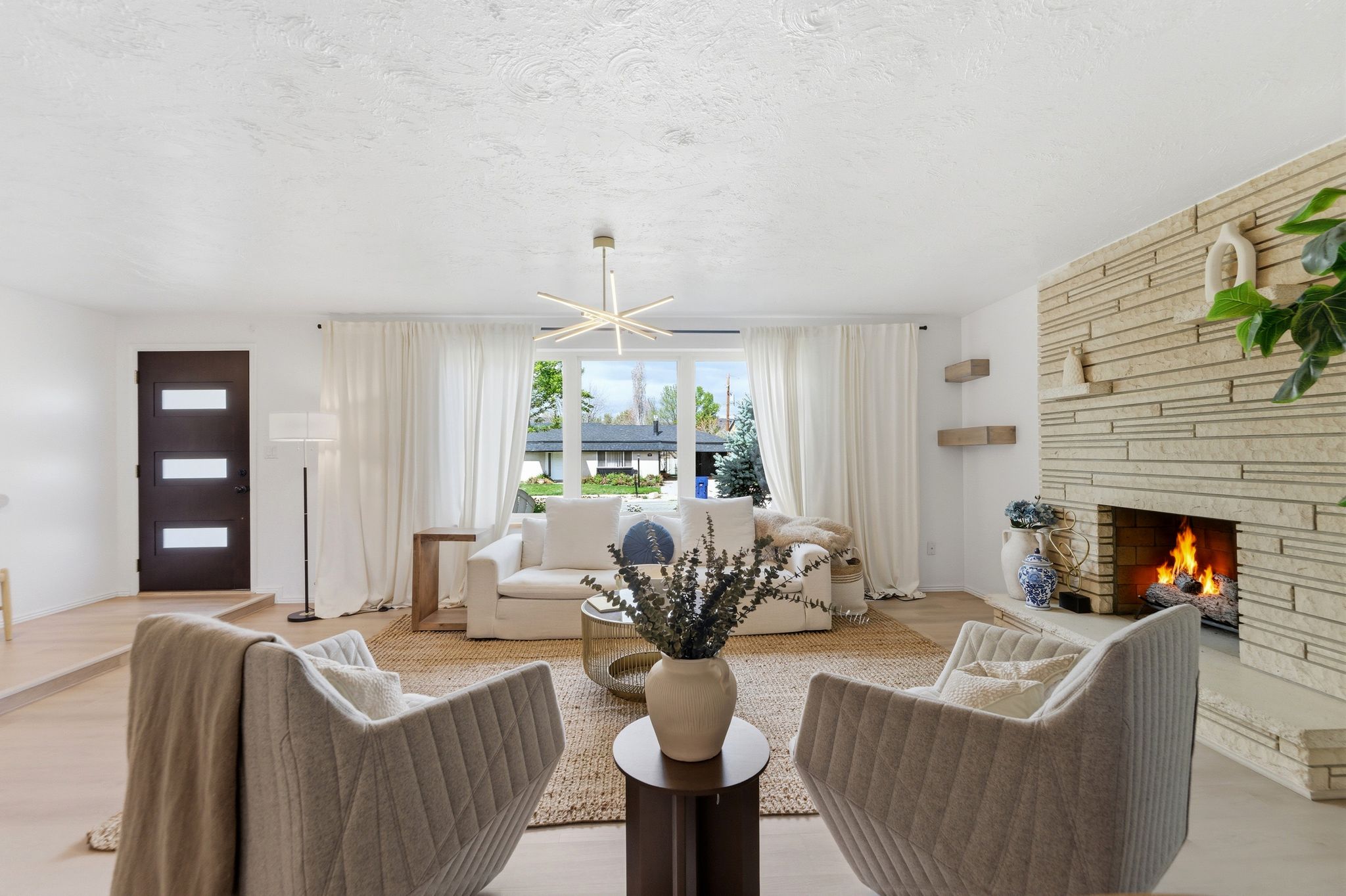 Living area with a fireplace, light wood finished floors, a textured ceiling, and a chandelier