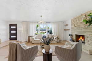Living area with a fireplace, light wood finished floors, a textured ceiling, and a chandelier