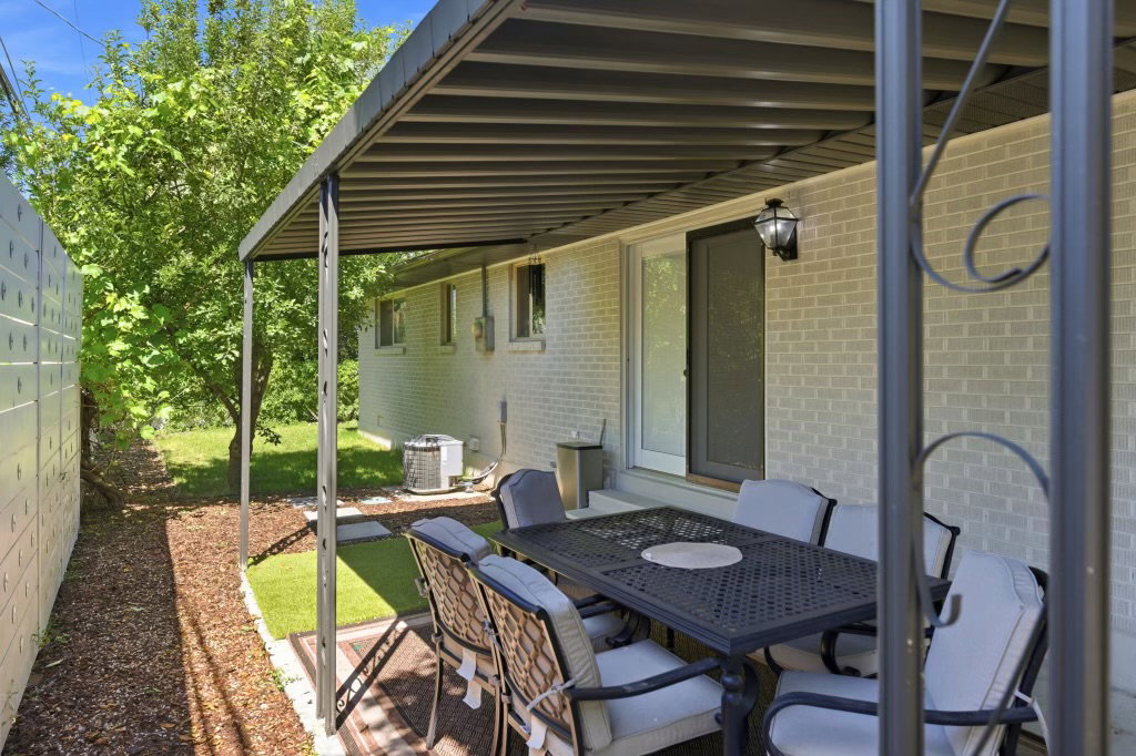 Covered patio area featuring a metal pergola structure, brick exterior, and a sliding glass door