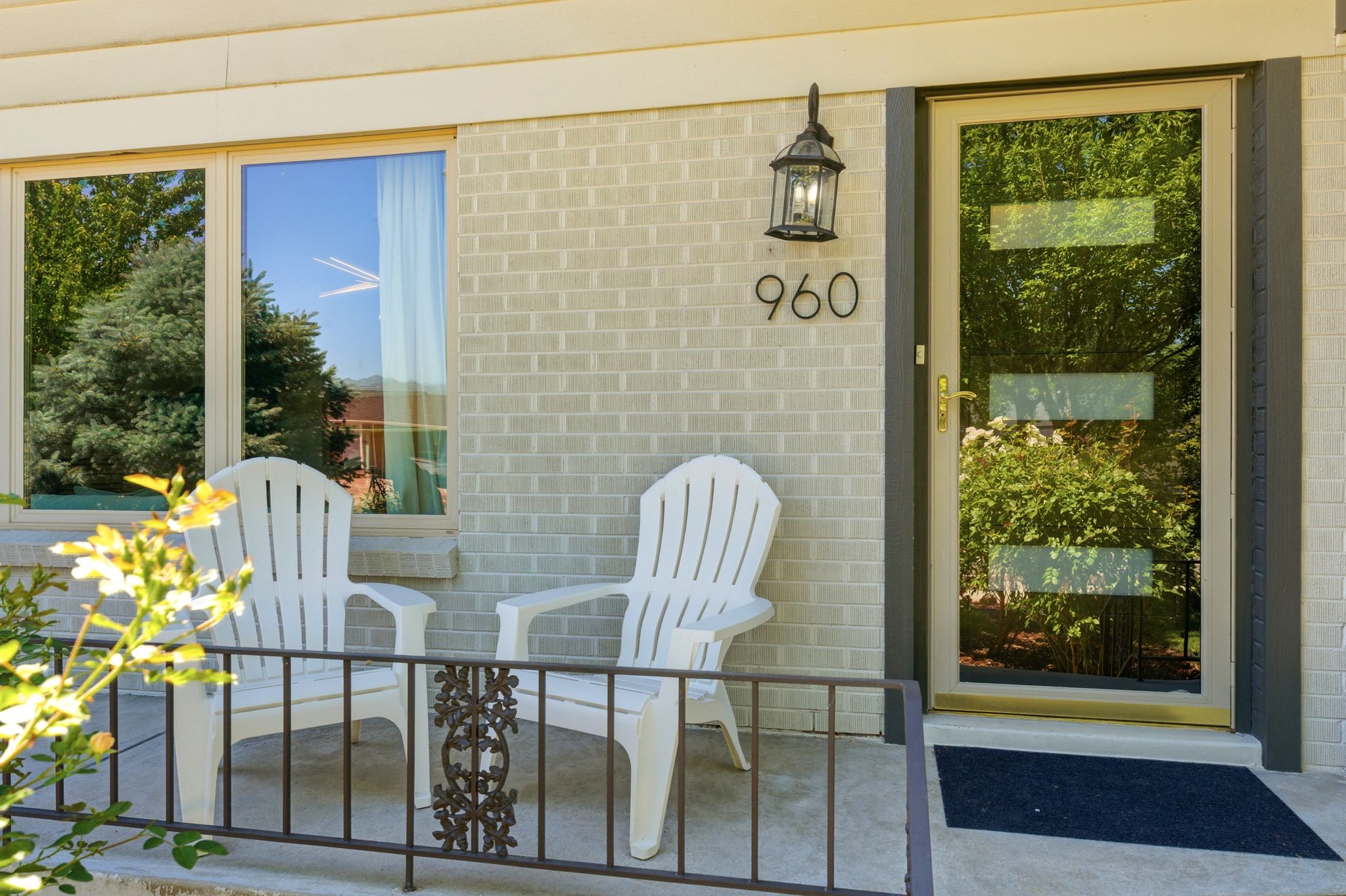 Brick facade entry featuring a full-light storm door with multiple glass panels, an exterior lantern light fixture, and large address numbers