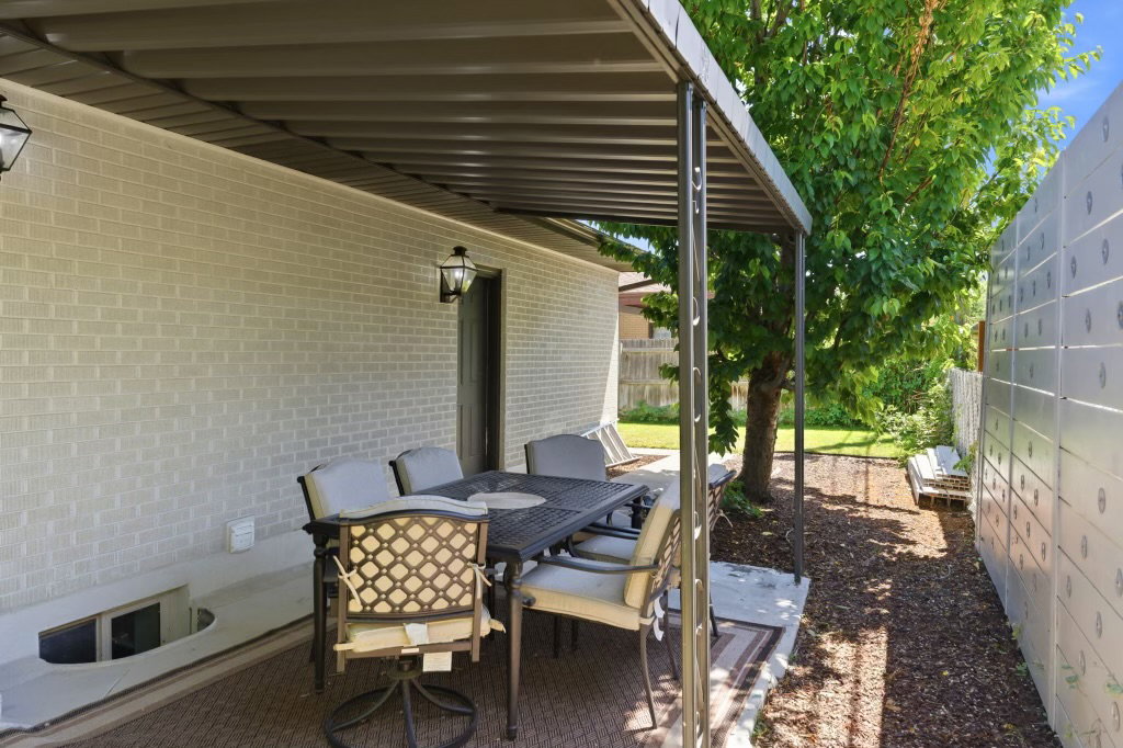 Outdoor patio space featuring a permanent pergola structure, brick exterior, and wall-mounted exterior lighting