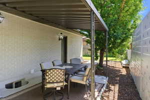 Outdoor patio space featuring a permanent pergola structure, brick exterior, and wall-mounted exterior lighting