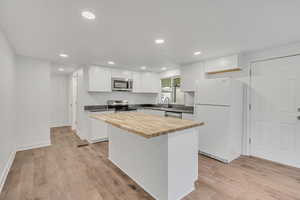 Kitchen featuring stainless steel appliances, butcher block countertops, white cabinetry, recessed lighting, and light wood-style floors