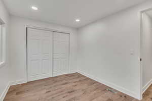 Unfurnished bedroom featuring light wood-type flooring, recessed lighting, and a closet