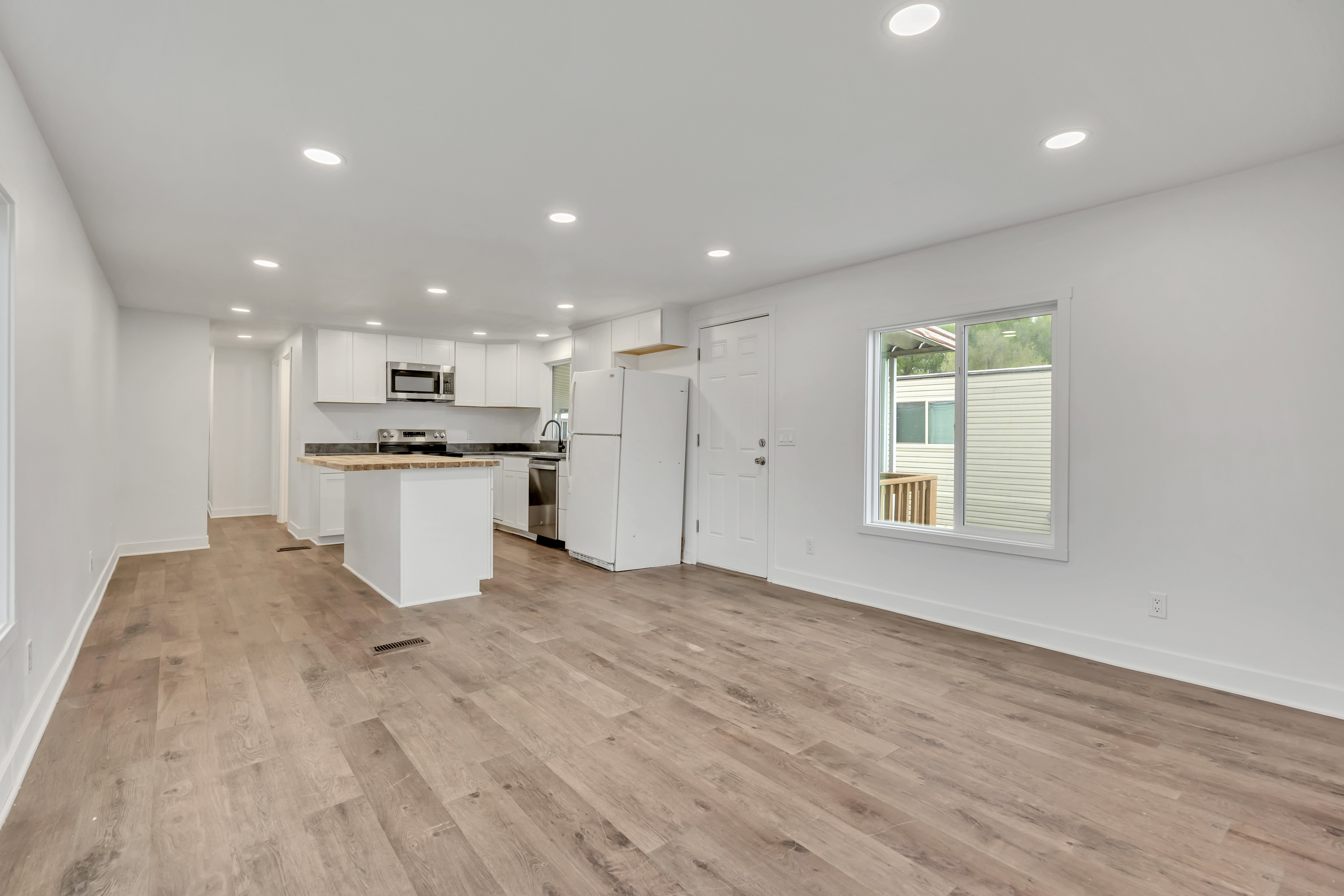 Kitchen with open floor plan, stainless steel appliances, recessed lighting, white cabinetry, and a kitchen island