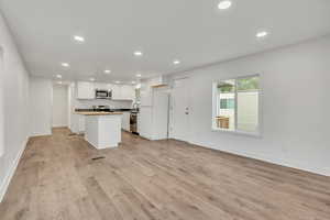 Kitchen with open floor plan, stainless steel appliances, recessed lighting, white cabinetry, and a kitchen island