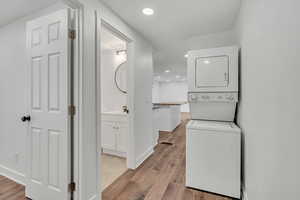 Laundry area featuring recessed lighting, light wood finished floors, and stacked washing machine and dryer