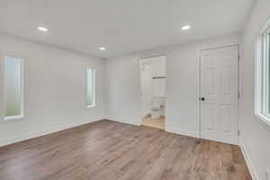 Unfurnished bedroom with recessed lighting, light wood-style flooring, multiple windows, and ensuite bathroom