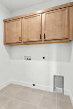 Laundry area featuring hookup for a washing machine, light tile patterned floors, cabinet space, and hookup for an electric dryer