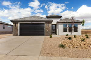Prairie-style home with an attached garage, concrete driveway, stone siding, stucco siding, and a tiled roof