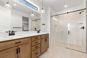 Full bath with double vanity, a shower stall, a walk in closet, recessed lighting, and light tile patterned flooring