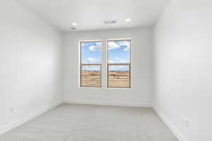Empty room with light carpet and recessed lighting