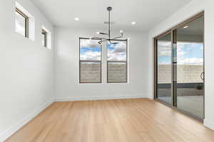 Unfurnished dining area with a chandelier and light wood-style flooring