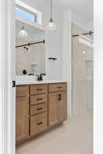 Bathroom with vanity, light tile patterned flooring, and a tile shower