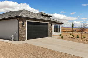 View of side of property featuring stone siding, concrete driveway, a garage, a tiled roof, and stucco siding