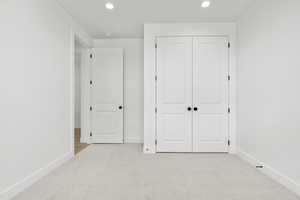 Unfurnished bedroom featuring light colored carpet, recessed lighting, and a closet
