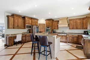 Kitchen featuring inlaid floor details, a kitchen bar, wood finish cabinetry, stainless steel appliances, and recessed lighting
